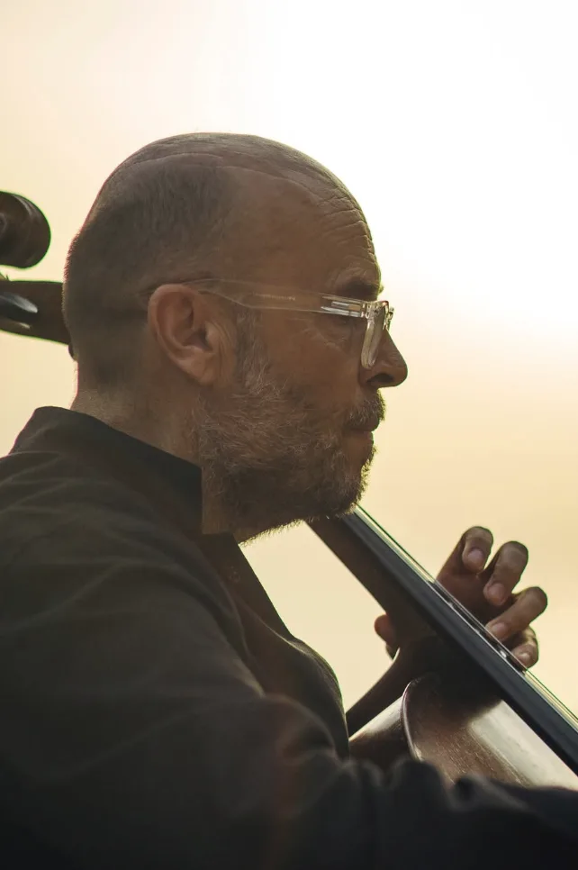 Violonchelista interpretando a contraluz del atardecer