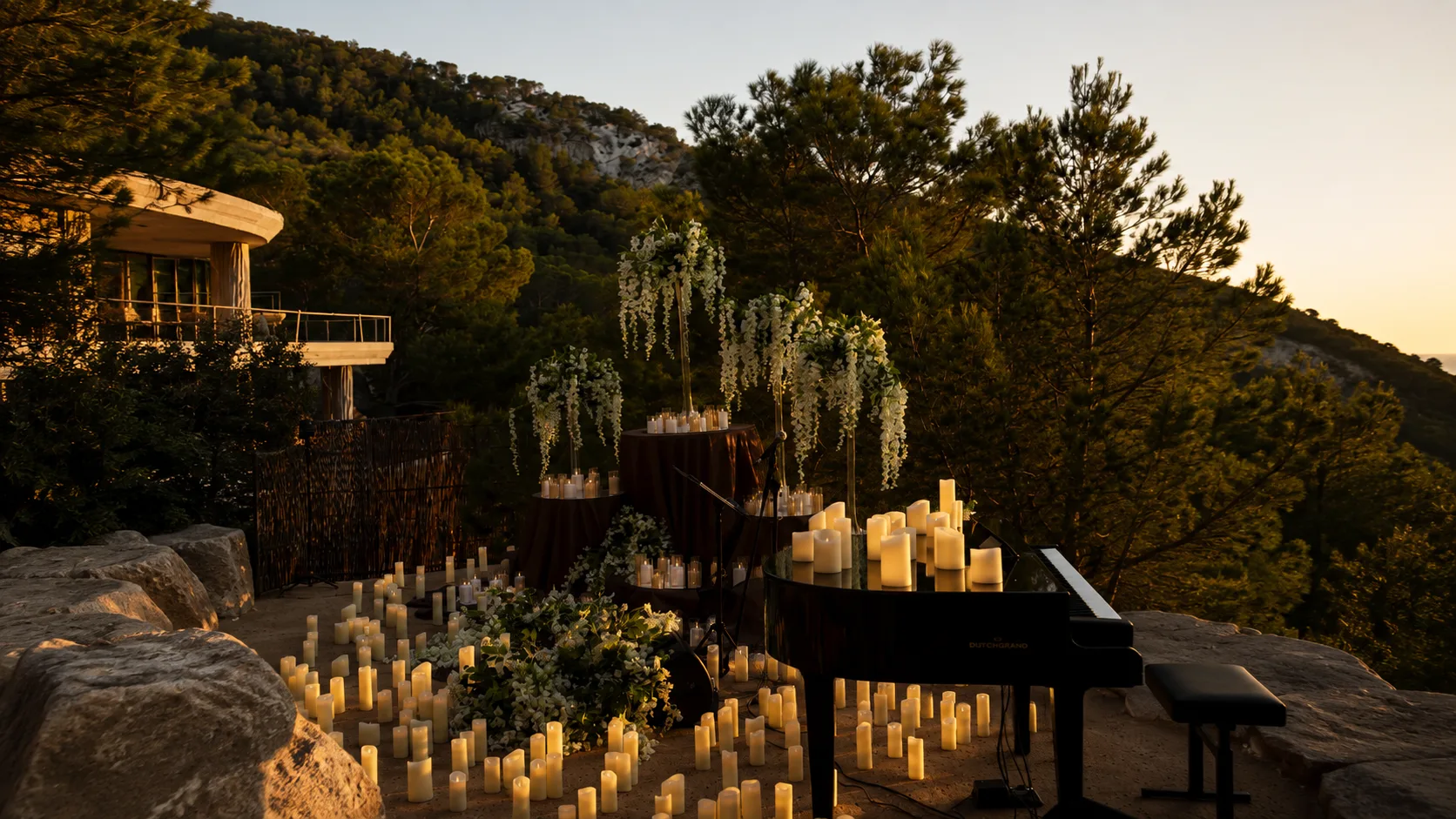 Piano de cola rodeado de cientos de velas y flores blancas al atardecer